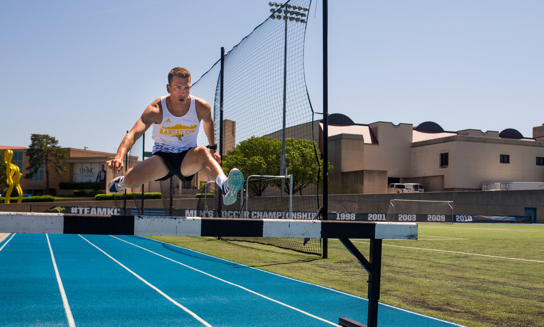 Bryce Miller jumps over a hurdle on the track